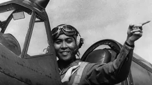 Foto, zwart/wit, van een vrouwelijke piloot in cockpit van klein vliegtuig, ten tijde van de oorlog te Indië.