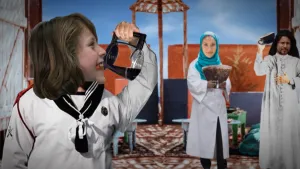 Foto van kinderen met koffie in de handen die toneelstuk opvoeren, decor op de achtergrond.