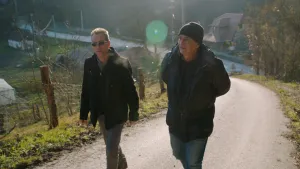 Foto van twee mannen die op een bospad lopen/wandelen.