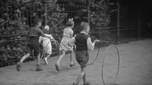 Foto, zwart/wit, van aantal kinderen die op de stoep aan het hoepelen zijn, zo ten tijde van de Tweede Wereldoorlog.