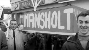 Foto, zwart/wit, van aantal personen bij een protestactie bij een groot bord met de tekst "mansholt" erop.