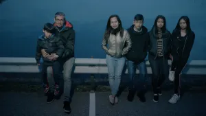 Foto van een aantal kinderen en een man op een weg langs de vangrail.