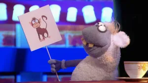 Foto van scène uit de Boterhamshow met Nico de Neushoorn (pop) die tekening van een aap vasthoudt.