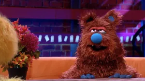 Foto van scène uit de Boterhamshow met de imker Wim van de Korf (pop) aan de desk en je ziet stukje van Opperdepop.