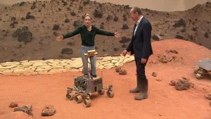 Foto van man en vrouw in een decor van een maanlandschap, de vrouw staat op een rijdend maankarretje.