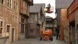 Foto van een nagemaakte stad met een hoogwerker waarin een man staat.