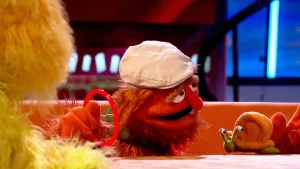 Foto van de Boterhamshow waarbij dierentrainer (pop) aan tafel zit met een slak, Snelle Jelle, Opperdepop zit er ook bij.