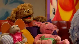 Foto van beeld uit Sesamstraat waarbij Pino, Ieniemienie, Purk en Tommie op de bank zitten om televisie te kijken.