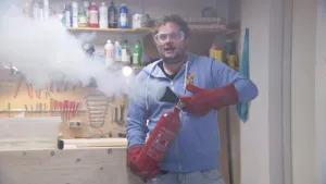 Foto van man, Diederik, die laat zien hoe een kleine brandblusser werkt.