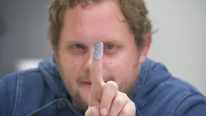 Foto, portret, van Diederik die wijsvinger opsteekt, de vingertop is afgedekt.