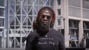 Foto van een man met bril op voor een modern (kantoor)gebouw.