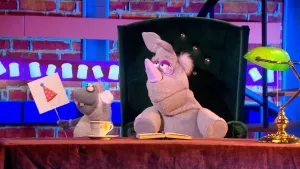 Foto van uitzending van Boterhamshow waarbij Nico de Neushoorn gedicht voordraagt en tekening van een muts vasthoudt.