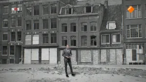 Foto van beeld uit het NOS-Journaal waarbij de nieuwslezer staat met erachter zwart/wit-foto van leegstaande huizen in stad, met puin op de straat.