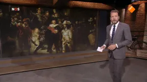 Foto van beeld van NOS-Journaal waarop de nieuwslezer staat bij de Nachtwacht.