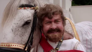 Foto van man verkleed als Keizer Caligula bij zijn paard.