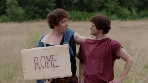 Foto van twee mannen verkleed als Romein, een ervan houdt een bord met Rome erop vast.