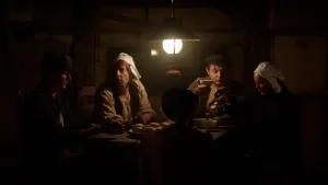 Een foto van vijf mensen die om een tafel heenzitten, waarop een bord met aardappels staat en ronde schaaltjes waar één vrouw iets in aan het schenken is. Eén man houdt een schaaltje omhoog. Ze beelden het schilderij De Aardappeleters van Van Gogh uit.