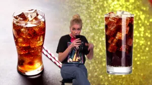 Een foto van Janouk die op een zwarte kruk zit en een slok neemt uit een glas cola. Naast Janouk zijn links en rechts foto's te zien van een glas cola met ijsklontjes erin. Naast het linkerglas liggen twee wit en rood gestreepte rietjes.