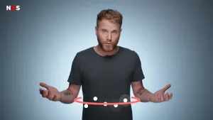 Een foto van een presentator met de handen met de handpalmen omhoog voor zijn lichaam. Tussen zijn handen en voor zijn buik staat een halve, rode cirkel met vijf witte bolletjes ertussen en om drie van de bolletjes staat een doorzichtig bolletje heen.
