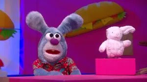 Een foto van een grijze konijn pop met rechts van de pop een kleine witte konijn knuffel die op een doos staat.