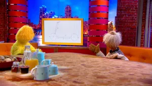 Een foto van Opper de Pop en pop professor Bolleboos die zitten en kijken naar een beeldscherm. Op het beeldscherm staat een met blauwe lijnen getekend voorbeeld van een step, met de groottes van de step in cijfers en met pijlen ernaast geschreven. 