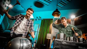 Een foto van presentatoren Buddy en Willem die in de studio aan het drummen zijn met spullen uit de keuken.