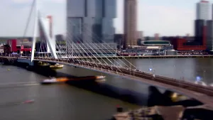 Een foto van een witte brug die over water heen loopt. Het middelste gedeelte van de brug, het deel waar verkeer overheen gaat, is scherp. De bovenkant, met lucht en grote gebouwen en onderkant met boten in het water zijn onscherp. 