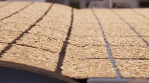 Een foto van een metalen, rond gedeelte links en een lopende band rechts. Van de lopende band vallen rechthoekige crackers met zaadjes van een lichte kleur erop op het metalen deel links, dat iets omhoog loopt of rolt naar een niet-zichtbaar gedeelte.