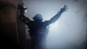 Een foto in een ruimte van witte stenen, met een fel licht achteraan. Janouk staat er verkleed als een monster, een zombie, met een soort doodshoofd als hoofd. De mond van het masker staat open in een uitroep en Janouk heeft de handen in de lucht geheven.