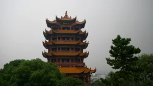 Een foto van een hoog gebouw met bruine daken op zes verschillende hoogtes. Van de daken steken de puntige uiteinden omhoog de lucht in. Op iedere verdieping zijn deuren te zien. Bovenaan is een Chinese tekst van vier tekens te zien op een bord. 