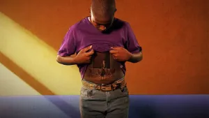 Een foto van Riquelme die zijn paarse t-shirt omhooghoudt en naar zijn buik kijkt. Hij fantaseert dat op zijn buik een man te zien is, die op vier hoge trommels speelt met twee stokken met witte bollen erop. 