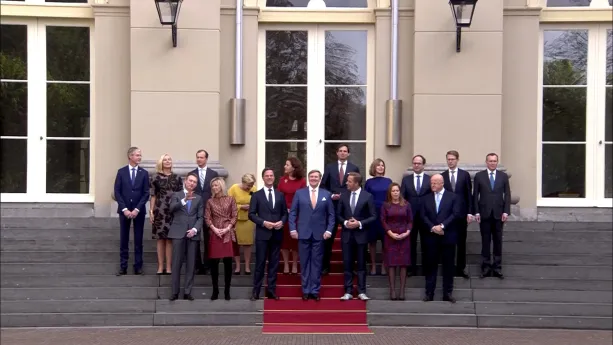 Een foto van het kabinet waarop alle ministers en vooraan koning Willem-Alexander, de minister-president Mark Rutte en viceminister-president Hugo de Jonge zien zijn. Ze staan op de trappen van het bordes van Paleis Huis ten Bosch op een rode loper.