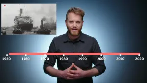 Een foto van een presentator achter een tijdlijn die loopt van 1950 tot 2020 in stappen van tien jaar. Linksboven is een zwart-wit foto met een grote boot in het water te zien, de boot waarop voor het eerst Molukkers naar Nederland kwamen in 1951.
