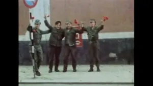 Een foto van vier mannen op 25 april 1974 in Portugal in een groen pak met een groene pet. Ze houden allemaal een rode anjer omhoog en staan op een weg bij een rond verkeersbord: blauw met een rode rand erom en rode streep erdoor. 