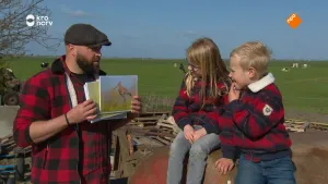 Een foto van boswachter Tim en twee jonge kinderen. Hij toont hen een foto van een weidevogel en zij kijken aandachtig ernaar.