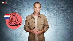 Een foto van een presentator met ernaast een zwart-wit getekend schip op een rode cirkel. Het is een zeilschip van vroeger, met zes zeilen. De Nederlandse vlag staat er in een cirkel naast. Op de achtergrond zijn twee ronde wereldkaarten te zien.