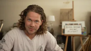 Een foto van presentator Pascal. Hij zit in een kamer kijkt in de camera.