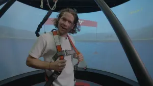 Een foto van presentator Pascal. Hij staat in een simulatie-ruimte waardoor het lijkt alsof hij in een luchtballon staat. 