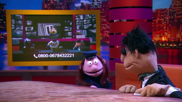 Een foto van pop meneer Goudstikker in zwart pak met zwart haar en een pop van een politieagent in een blauw politiepak met pet op. Meneer goudstikker kijkt naar een beeldscherm met een telefoonnummer erop en zes politiepoppen achter een telefoon.