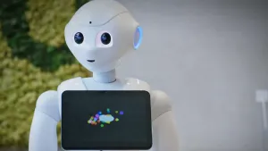 Een foto van een witte robot die wel wat op een mens lijkt. Op zijn borst heeft hij een beeldscherm. 