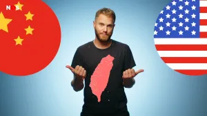 Een foto van een presentator en daarvoor in rood het getekende eiland Taiwan. Hij wijst met zijn duimen naar twee ronde vlaggen: de rode vlag met gele sterren van China, en de rood-wit gestreepte vlag met witte sterren in een blauwe rechthoek van Amerika.
