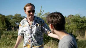Een foto van de presentatoren Pieter en Willem. Ze staan buiten in de natuur en de zon schijnt. Ze zijn 's zomers gekleed en kijken elkaar aan. Pieter heeft een zonnebril op.