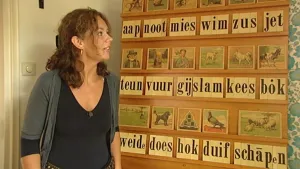 Een foto van een vrouw die naast een aap, noot, mies leesplankje staat en ernaar kijkt.