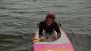 Een foto van presentator Pascal die in water ligt op een foil board. Een foil board is een soort surfboard.