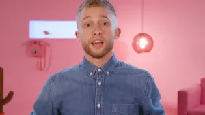 Een foto van presentator Jard. Hij heeft een spijkerjasje aan en legt iets uit aan de kijker. Op de achtergrond zie je een roze muur met daarop een roze telefoon. Ook zie je een roze hanglamp en een roze bank.