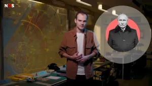 Een foto van een presentator en een ronde, rode cirkel met zwart-wit foto van Vladimir Poetin in zwarte jas. Erachter hangt een kaart met gele lijnen en cirkels en staat een tafel met een naambordje, een oude, zwarte telefoon met draaischijf en papieren.