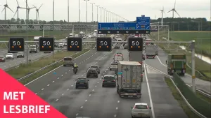 Een foto van een drukke snelweg. Boven de snelweg staan er borden aan waar 50 opstaat van maximaal 50 kilometer per uur. Linksonder staat de tekst 'Met lesbrief'.