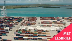 Een foto van een haven gezien vanuit de lucht. Je ziet honderden zeecontainers en een havenkraan. Daarachter zie je de zee met daarin enkele eilanden. In een hoek van het beeld staat de tekst 'Met lesbrief'.