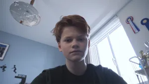 Een foto van Jesper, die met een verdrietige blik naar de camera beneden kijkt en vertelt over seksueel misbruik. Erachter staat een zwarte tekening op de muur van twee mensen die van een duikplank springen en staan en hangen prijzen: bekers en lintjes.