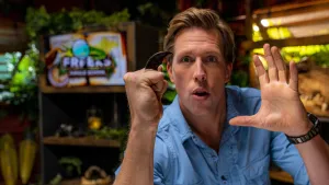 Een foto van presentator Freek die in de studio staat en met een hand een vuist maakt. In zijn vuist heeft hij een klauw van een ijsbeer tussen zijn vingers.